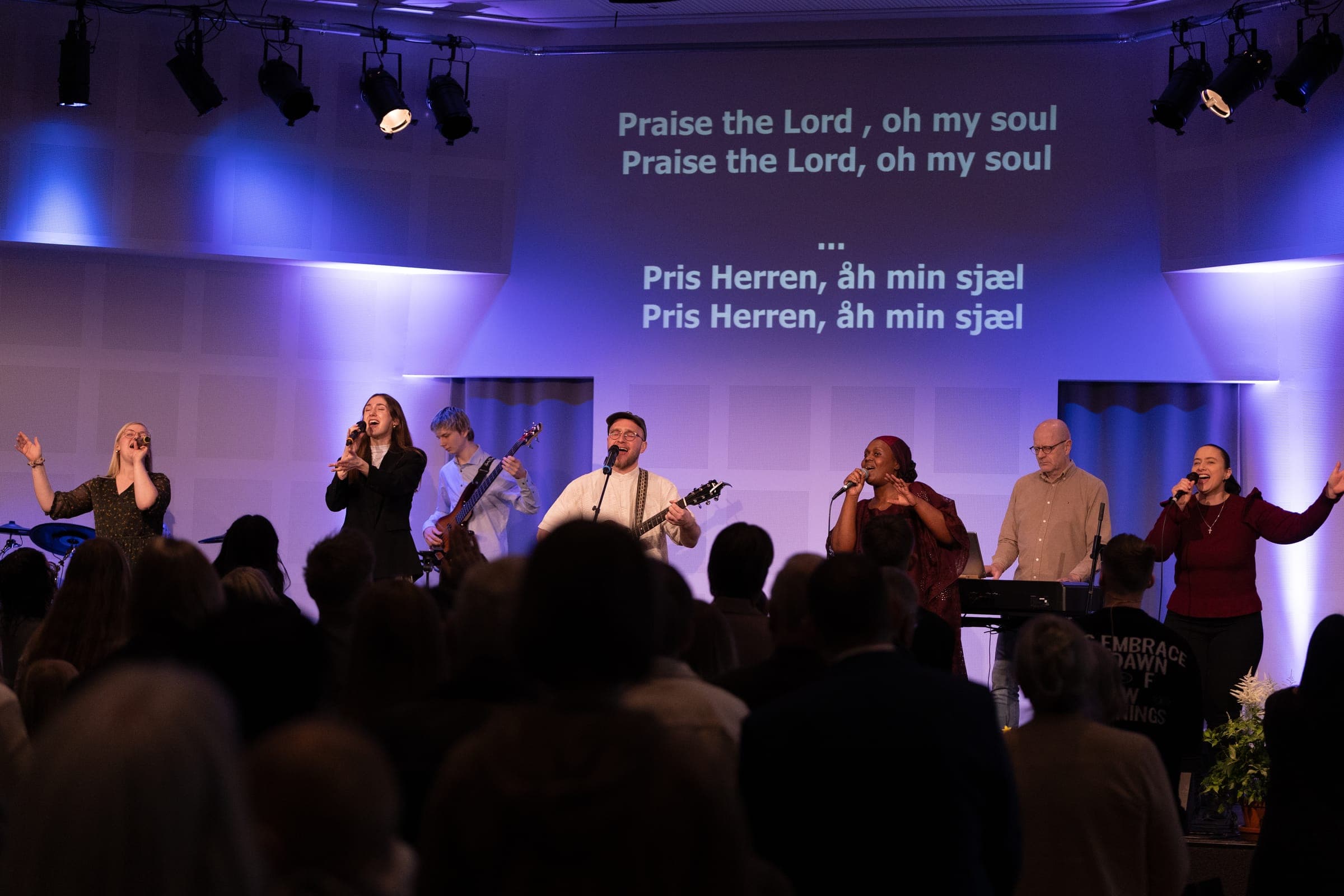 The worship team leading the congregation in song, with the lyrics projected behind the stage